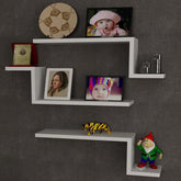 Rafturi albe moderne pe un perete gri, decorate cu fotografii și obiecte – primabucata